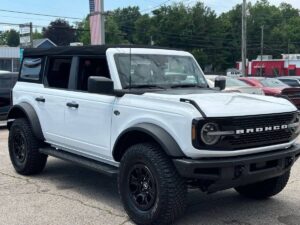 2022 Ford Bronco in rugged outdoor setting, showcasing its robust design, off-road tires, high ground clearance, and classic grille style.