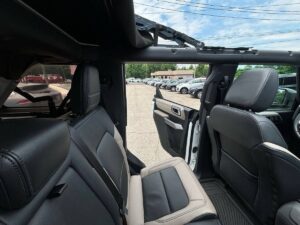 2022 Ford Bronco in rugged outdoor setting, showcasing its robust design, off-road tires, high ground clearance, and classic grille style.