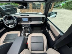 2022 Ford Bronco in rugged outdoor setting, showcasing its robust design, off-road tires, high ground clearance, and classic grille style.