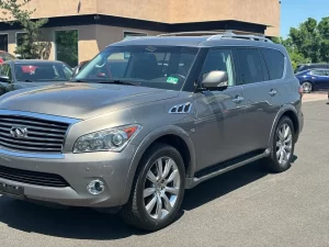 A 2014 INFINITI QX80 parked on a scenic road, showcasing its sleek design and premium luxury SUV features.