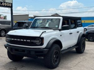 2022 Ford Bronco in rugged outdoor setting, showcasing its robust design, off-road tires, high ground clearance, and classic grille style.