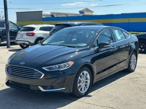 2020 Ford Fusion Hybrid in a sleek silver exterior, showcasing its modern design and hybrid efficiency on the road.