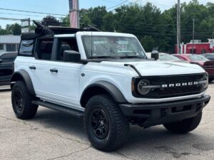 2022 Ford Bronco in rugged outdoor setting, showcasing its robust design, off-road tires, high ground clearance, and classic grille style.