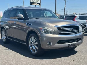 A 2014 INFINITI QX80 parked on a scenic road, showcasing its sleek design and premium luxury SUV features.