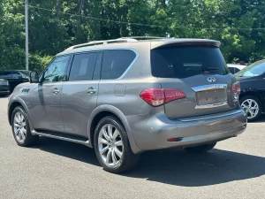 A 2014 INFINITI QX80 parked on a scenic road, showcasing its sleek design and premium luxury SUV features.