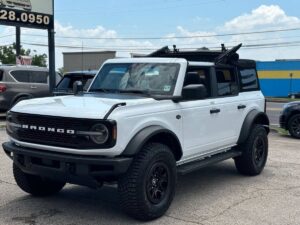 2022 Ford Bronco in rugged outdoor setting, showcasing its robust design, off-road tires, high ground clearance, and classic grille style.