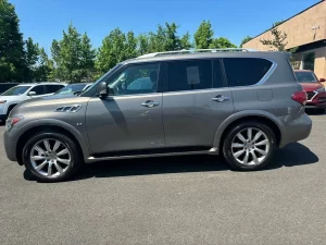 A 2014 INFINITI QX80 parked on a scenic road, showcasing its sleek design and premium luxury SUV features.