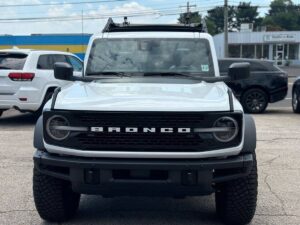 2022 Ford Bronco in rugged outdoor setting, showcasing its robust design, off-road tires, high ground clearance, and classic grille style.