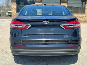 2020 Ford Fusion Hybrid in a sleek silver exterior, showcasing its modern design and hybrid efficiency on the road.