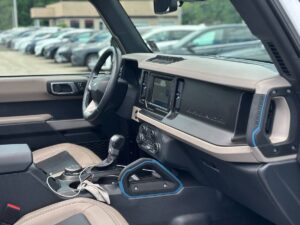 2022 Ford Bronco in rugged outdoor setting, showcasing its robust design, off-road tires, high ground clearance, and classic grille style.