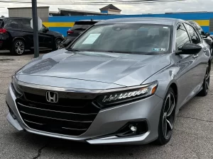 A sleek 2021 Honda Accord in a scenic outdoor setting, showcasing its modern design, bold grille, and premium features.