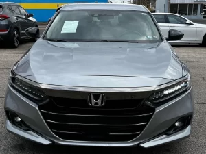 A sleek 2021 Honda Accord in a scenic outdoor setting, showcasing its modern design, bold grille, and premium features.