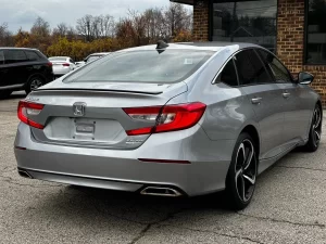 A sleek 2021 Honda Accord in a scenic outdoor setting, showcasing its modern design, bold grille, and premium features.